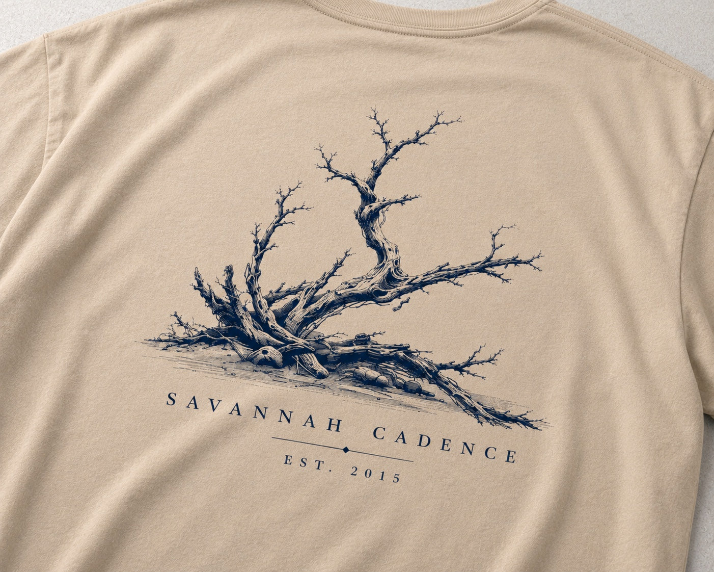 Close-up of the Savannah Cadence Driftwood tree artwork on a sand Driftwood Tee