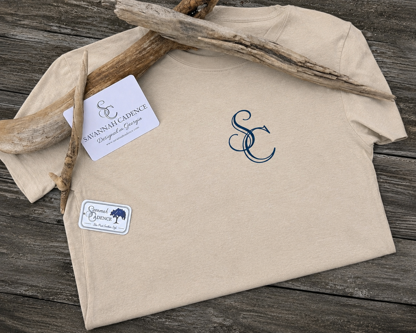 Savannah Cadence Driftwood Tee styled flat lay featuring the left chest logo, driftwood, and Savannah Cadence branding