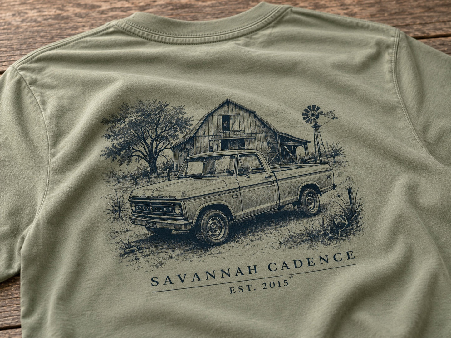 Close-up detail of the back artwork featuring a vintage pickup truck, barn, and windmill on a Light Olive Next Level 6210 shirt.